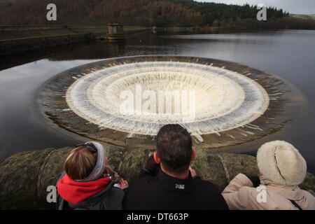 Spaziergänger beobachten Überlaufwasser Tauchen Sie ein in einen Schacht in Ladybower Vorratsbehälter, Upper Derwent Valley, Peak District Derbyshire UK Stockfoto