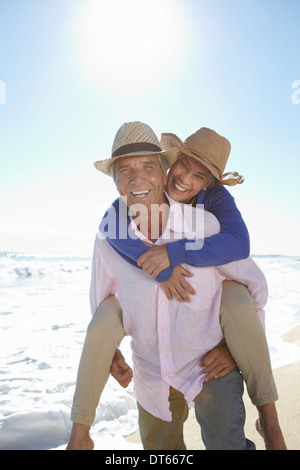 Mann-Piggy-Unterstützung-Frau am Strand Stockfoto