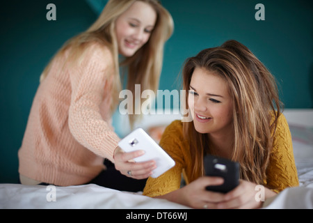 Zwei Mädchen im Teenageralter Blick auf Smartphones im Schlafzimmer Stockfoto