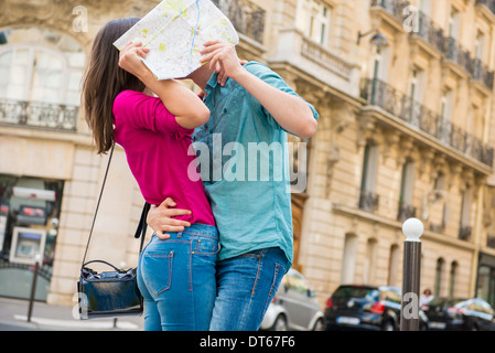 Junges Paar versteckt sich hinter Karte, Paris, Frankreich Stockfoto