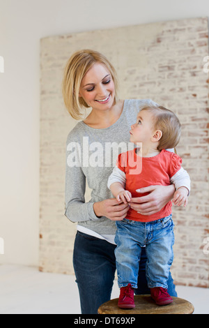 Studio-Porträt der Mutter hält Tochter auf Hocker Stockfoto