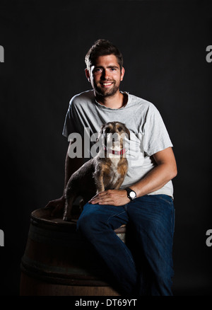 Porträt der Winzer und sein Hund sitzt auf Weinfass Stockfoto