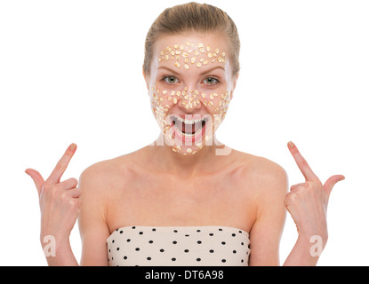 Glückliche junge Frau zeigte auf Haferflocken Maske Stockfoto