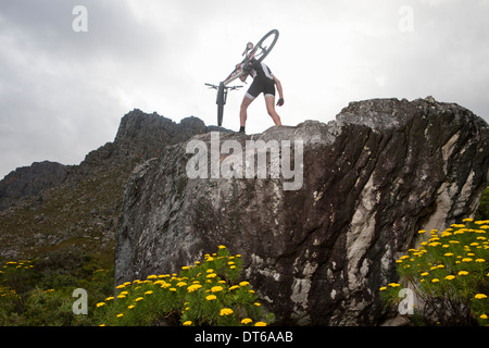 Junger Mann mit Mountain-Bike auf Felsformation Stockfoto