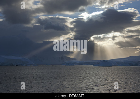 Die Sonne bricht durch die Wolken schlagen die Eisberge entlang der Westküste der antarktischen Halbinsel. Stockfoto