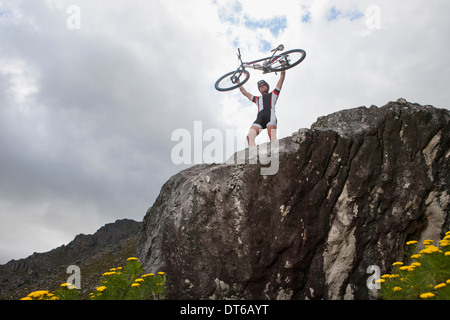 Junger Mann hält Mountainbike auf Felsen Stockfoto