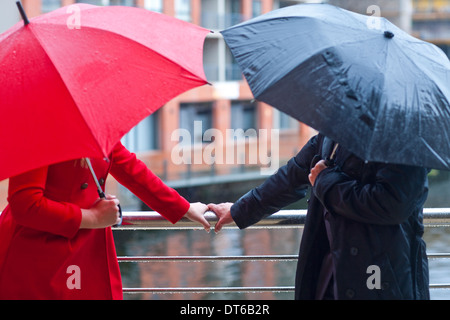Symmetrische Paar holding Handlauf und Durchführung des Regenschirmes Stockfoto