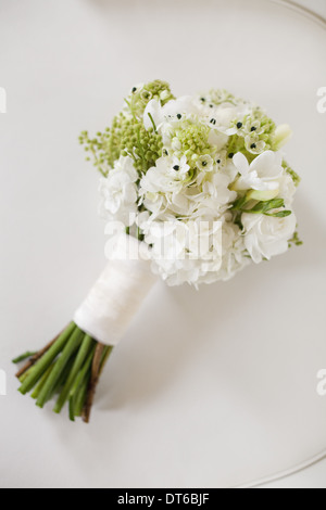 Ein Brautstrauß. Weiße Blumen, grüne Samenköpfe und Laub. Grüne Stiele und weißes Band. Stockfoto