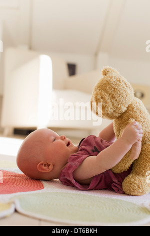 Babymädchen spielen mit Teddybär Stockfoto