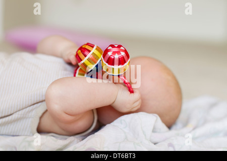 Babymädchen liegend mit Rassel für Gesicht Stockfoto