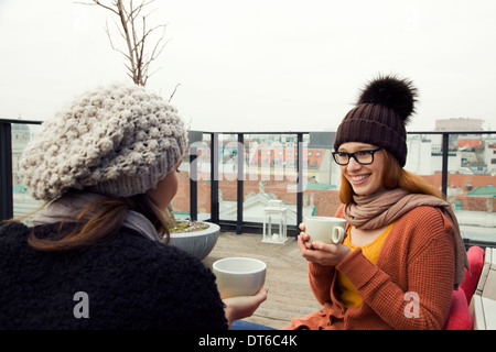 Zwei junge Erwachsene Frauen mit Kaffee auf der Dachterrasse Stockfoto