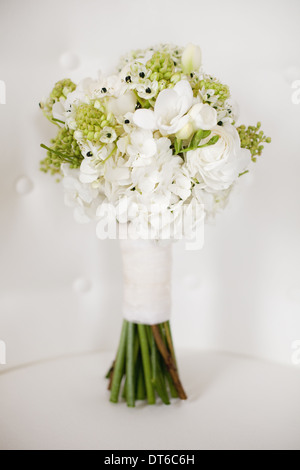 Ein Brautstrauß. Weiße Blumen, grüne Samenköpfe und Laub. Grüne Stiele und weißes Band. Stockfoto