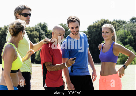 Ältere männliche Trainer und eine Gruppe von Erwachsenen Läufer betrachten Stoppuhr Stockfoto