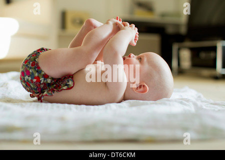 Babymädchen auf Rücken mit Füßen spielen Stockfoto