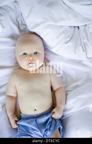 Babymädchen liegen auf Bettwäsche Stockfoto