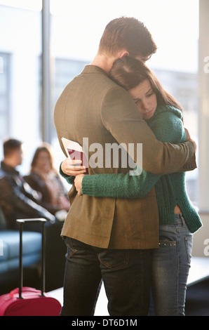 Junges Paar umarmt in Flughafen Stockfoto