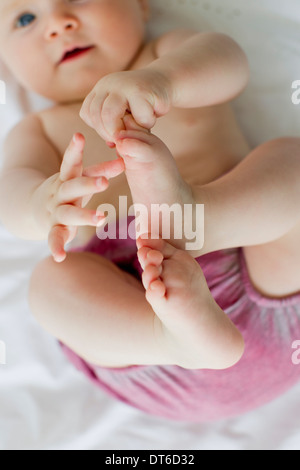 Babymädchen spielen mit Füßen Stockfoto