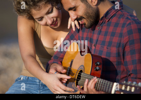 Junges Paar, Mann spielt Gitarre Stockfoto