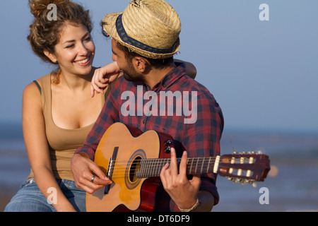 Junges Paar, Mann spielt Gitarre Stockfoto