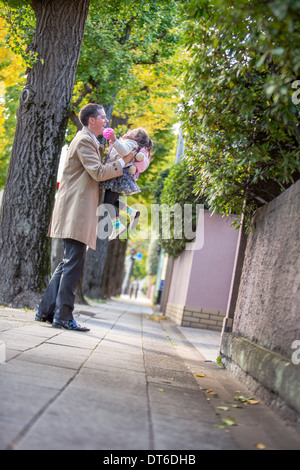 Anhebende Tochter Vater auf Bürgersteig Stockfoto