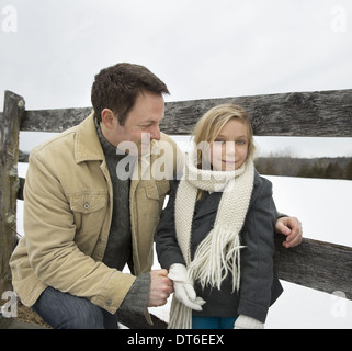 Ein Mann und ein Kind stützte sich auf einen Zaun im Freien.  Ein Bauernhof im Schnee. Stockfoto