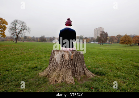 Mann sitzt auf Baumstumpf anhören von Musik Stockfoto