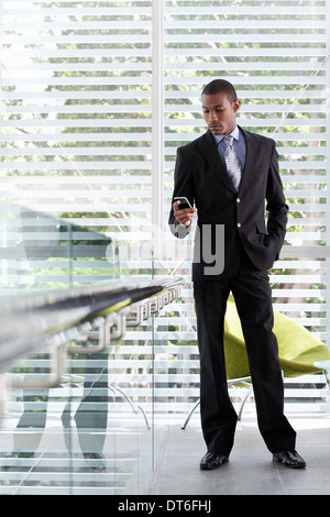 Geschäftsmann mit SMS auf Handy im Büro