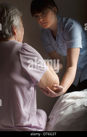 Körperpflege-Assistent hilft senior Frau aufstehen Stockfoto