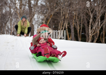 Mutter, die gerade zwei junge Töchter Schlittenfahren im Schnee Stockfoto