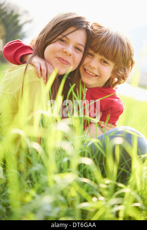 Schwester und Bruder in der Wiese sitzen Stockfoto