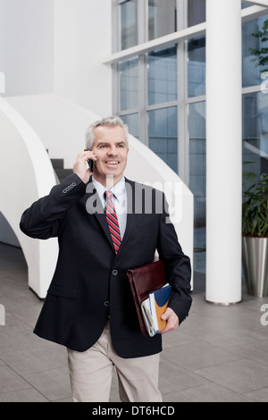 Unternehmer, die im Chat auf Handy im Büro atrium Stockfoto