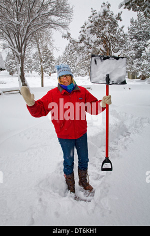 Eine Frau, Schneeschaufeln von ihrem Deck oder vorderen Veranda auf einem Landsitz in Zentral-Oregon in einen ordentlichen Schneesturm. Stockfoto