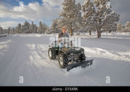 Eine Seniorin Pflüge Schnee mit einem ATV, all-Terrain-Fahrzeug, nach einem großen Schneesturm in Zentral-Oregon. Stockfoto