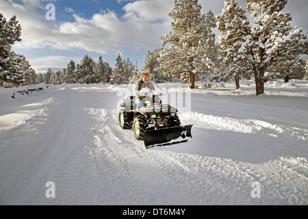 Eine Seniorin Pflüge Schnee mit einem ATV, all-Terrain-Fahrzeug, nach einem großen Schneesturm in Zentral-Oregon. Stockfoto