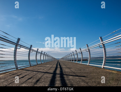 Handläufe und Schatten auf einem Wellenbrecher schwinden in der Ferne. Stockfoto