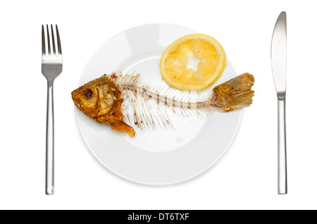 Fisch-Skelett mit gepresste Zitrone auf dem Teller - Symbol für Nahrungsmittelknappheit und Elend. Isoliert auf weißem Hintergrund. Stockfoto