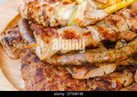 Spieß, gegrilltes Schweinefleisch, Würstchen und Koteletts mit Kartoffeln Stockfoto