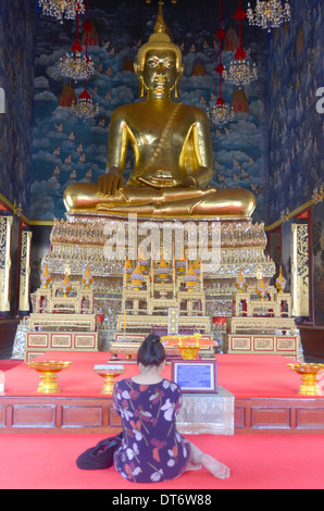 Große goldene sitzende Buddha-Statue im Wat, Bangkok Thailand mit Frau beten Stockfoto