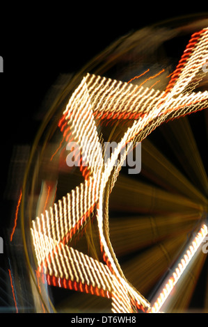 Riesenrad in der Nacht. Abstrakt verschwommene Formen Vergnügungspark Lichter in Bewegung. Stockfoto