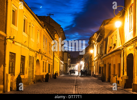 Brasov, Transylvania. Nachtaufnahme des Mittelalters gepflasterte Strasse in der Innenstadt der Stadt. Sächsischer Meilenstein in Rumänien. Stockfoto