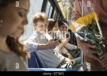 Urbaner Lifestyle. Eine Gruppe von Menschen, Männer und Frauen auf einem Stadtbus in New York City. Zwei Personen überprüfen ihre Smartphones. Stockfoto