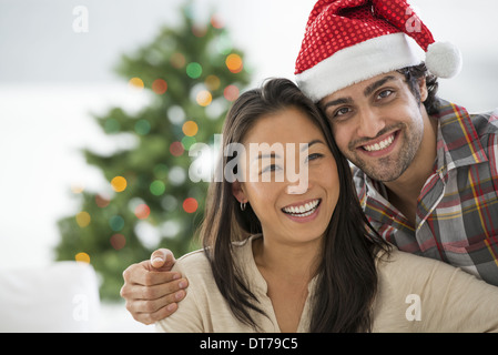 Ein Mann in eine Weihnachtsmann-Mütze. Zuhause. Ein geschmückter Weihnachtsbaum. Stockfoto