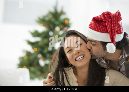 Ein Mann in eine Weihnachtsmann-Mütze. Zuhause. Ein geschmückter Weihnachtsbaum. Stockfoto