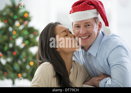 Ein Mann in eine Weihnachtsmann-Mütze. Zuhause. Ein geschmückter Weihnachtsbaum. Stockfoto