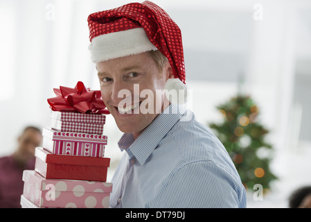 Ein Mann in eine Weihnachtsmann-Mütze. Zuhause. Ein geschmückter Weihnachtsbaum. Stockfoto