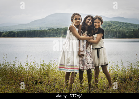 Drei junge Mädchen stehen an der Seite eines Sees, umarmen einander Woodstock New York USA Stockfoto