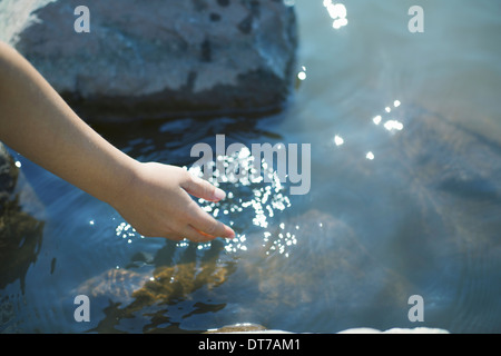 Ein junges Mädchen nach vorne lehnen, um ihre Hand zu klaren seichten Seewasser Ashokan New York USA U S Stockfoto