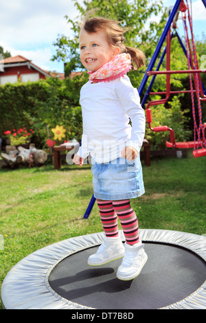 Mädchen springen auf dem Trampolin im Garten Stockfoto