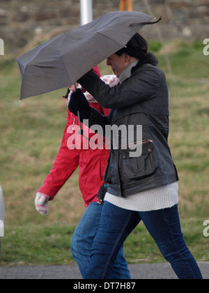 Frau mit Regenschirm in den windigen Bedingungen zu kämpfen. Stockfoto