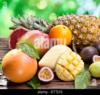 Exotische Früchte auf einem Holztisch mit dunkelgrünem Laub auf dem Hintergrund. Stockfoto